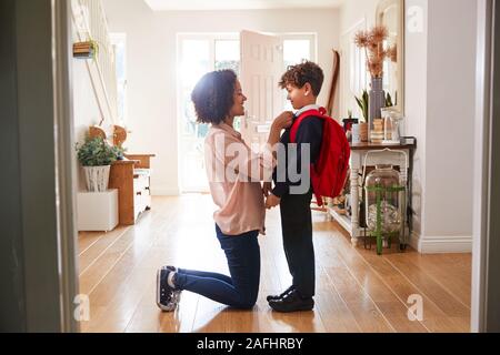 Single Mother At Home Getting Son Wearing Uniform Ready For First Day Of School Stock Photo