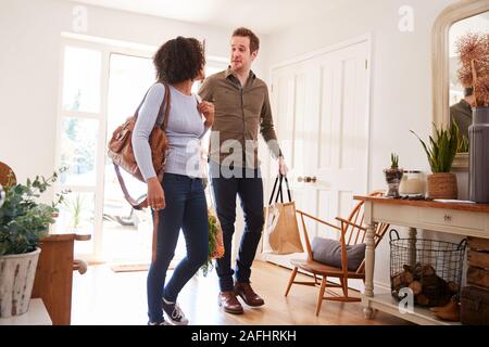 Mature Couple Returning Home From Shopping Trip Carrying Groceries In Plastic Free Bags Stock Photo