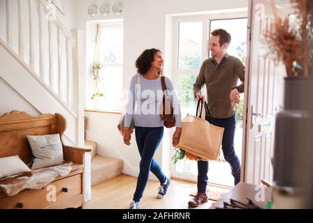 Mature Couple Returning Home From Shopping Trip Carrying Groceries In Plastic Free Bags Stock Photo