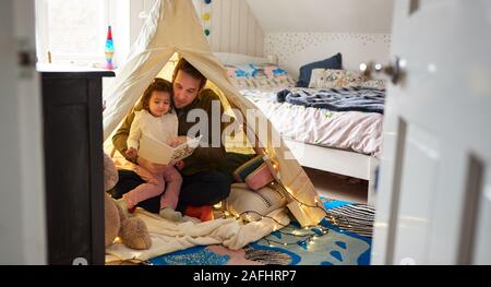 Single Father Reading With Daughter In Den In Bedroom At Home Stock Photo