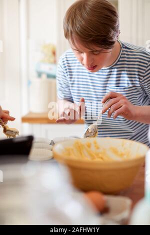 Young Downs Syndrome Man Baking Cupcakes In Kitchen At Home Stock Photo