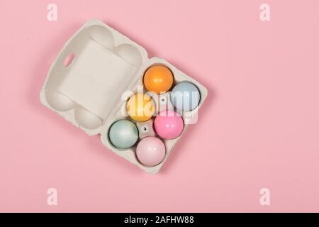 Easter background with a carton egg box with pastel colored easter eggs in it on a pink background Stock Photo