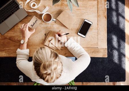 Overhead Shot Looking Down On Woman Writing In Generic Thank You Card Stock Photo