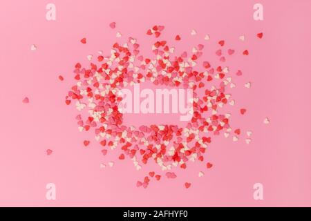 frame on a pink background made of small sweet multi-colored candy hearts. Copy space. View from above Stock Photo