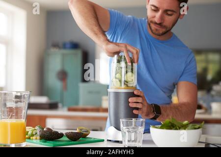 Man Making Healthy Juice Drink With Fresh Ingredients In Electric Juicer After Exercise Stock Photo