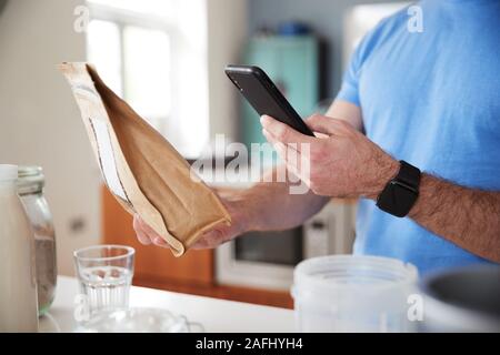 Man Wearing Fitness Clothing Scanning QR Code On Food Packaging To Find Nutritional Information Stock Photo