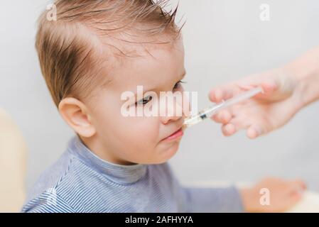 mom gives the boy fish oil through a syringe Stock Photo