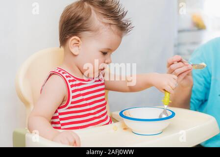 Mom feeds the child buckwheat porridge in the kitchen Stock Photo