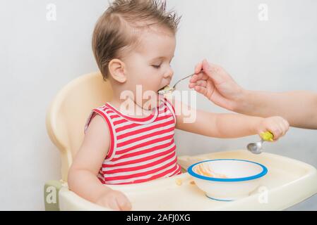 Mom feeds the child buckwheat porridge in the kitchen Stock Photo