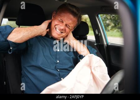 Male Motorist With Whiplash Injury In Car Crash With Airbag Deployed Stock Photo