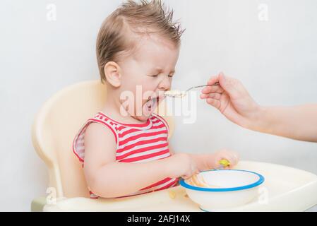 Mom feeds the child buckwheat porridge in the kitchen Stock Photo