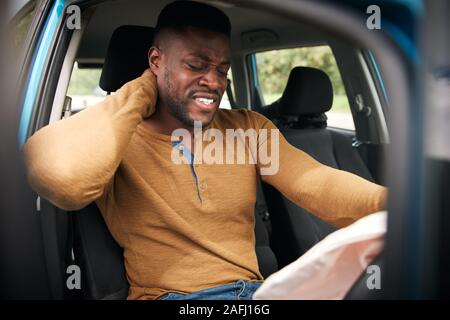 Male Motorist With Whiplash Injury In Car Crash With Airbag Deployed Stock Photo