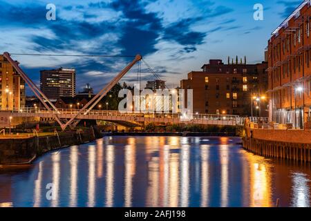 LEEDS, UNITED KINGDOM - AUGUST 13: City view of a footbridge and riverside buildings along the River Aire at dusk on August 13, 2019 in Leeds Stock Photo