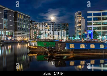 LEEDS, UNITED KINGDOM - AUGUST 13: This is a night view of riverside city buildings and boats anchored at Leeds Dock on August 13, 2019 in Leeds Stock Photo