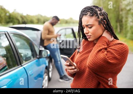 Female Motorist Involved In Car Accident Calling Insurance Company Or Recovery Service Stock Photo