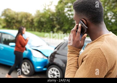 Male Motorist Involved In Car Accident Calling Insurance Company Or Recovery Service Stock Photo