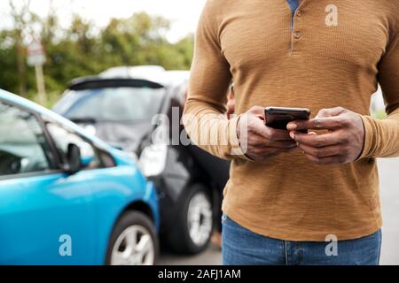 Male Motorist Involved In Car Accident Calling Insurance Company Or Recovery Service Stock Photo