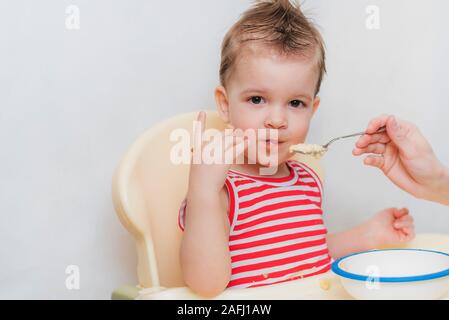 Mom feeds the child buckwheat porridge in the kitchen Stock Photo