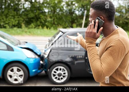 Male Motorist Involved In Car Accident Calling Insurance Company Or Recovery Service Stock Photo