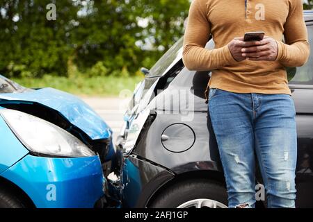Male Motorist Involved In Car Accident Calling Insurance Company Or Recovery Service Stock Photo