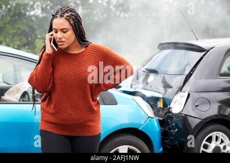 Female Motorist Involved In Car Accident Calling Insurance Company Or Recovery Service Stock Photo