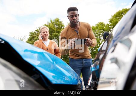 Male Motorist Involved In Car Accident Taking Picture Of Damage For Insurance Claim Stock Photo