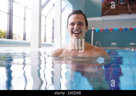 Portrait Of Male Swimmer Warming Up In Swimming Pool Stock Photo