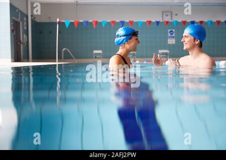 Male Swimming Teacher Giving Woman One To One Lesson In Pool