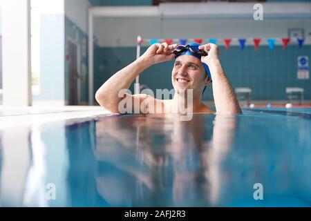 Male Swimmer Wearing Hat And Goggles Training In Swimming Pool Stock Photo