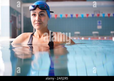 Female Swimmer Wearing Hat And Goggles Training In Swimming Pool Stock Photo
