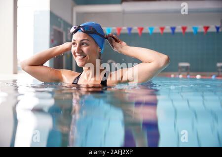 Female Swimmer Wearing Hat And Goggles Training In Swimming Pool Stock Photo
