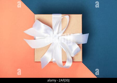 Trendy attractive minimalistic gift on the coral and blue background. Merry Christmas, St. Valentine's Day, Happy Birthday and other holidays concept. Stock Photo