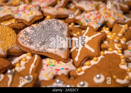 Many colorful handmade gingerbread cookies baked and decorated for Christmas Holidays. Silver and gold balls on iced  candys in different shapes Stock Photo