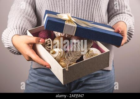 Big blue box with christmas decorations and ribbon in female hands. Preparing for Christmas concept. Stock Photo