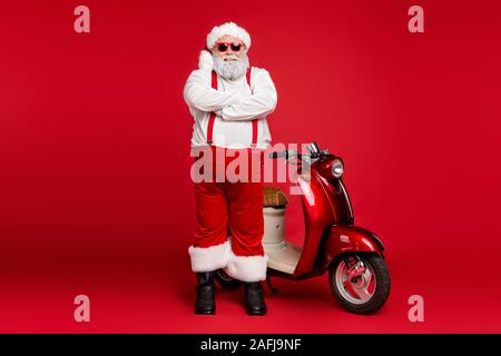 Full length body size view of his he nice bearded cheerful content funky cool Santa Claus hipster standing near motor bike folded arms isolated on