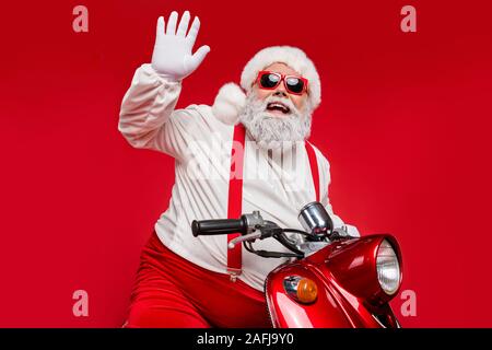 Portrait of his he nice bearded cheerful funky Santa hipster riding motor bike waving congratulating you North Pole congrats isolated on bright vivid