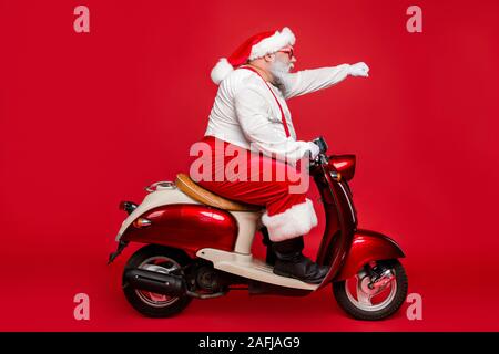 Profile side view portrait of nice bearded serious purposeful Santa Claus father riding moped delivering purchases hurry up shopping season isolated Stock Photo