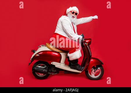 Profile side view portrait of nice bearded cheerful funny funky purposeful Santa Claus riding moped hurry up shopping season North Pole isolated on