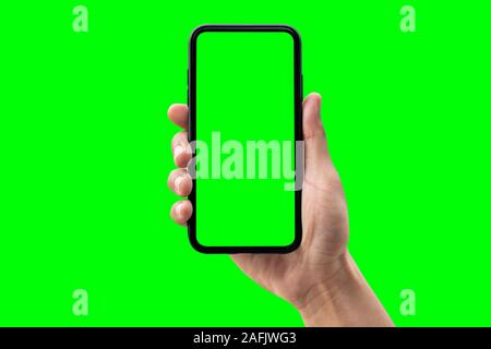 Hand holding smartphone isolated on green background. Stock Photo