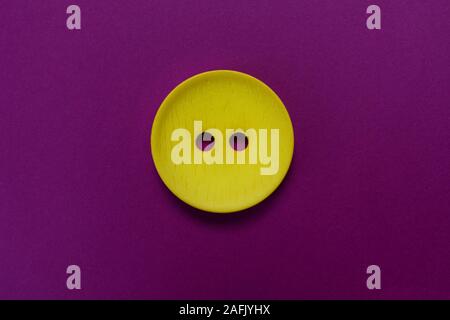 Big yellow button isolated on a purple background. Stock Photo