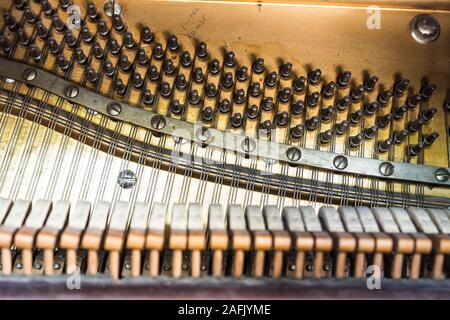 Inside view of old player piano: hammers, strings, tuning pegs, and metal sound board Stock Photo