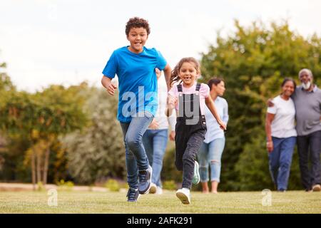 Children Running Ahead As Multi-Generation Mixed Race Family Walking In Garden At Home