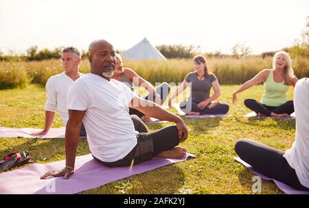 Female Teacher Leading Group Of Mature Men And Women In Class At Outdoor Yoga Retreat Stock Photo
