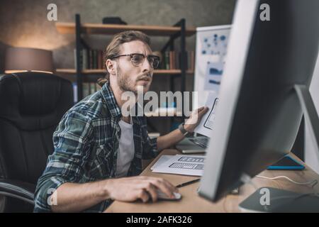 Young bearded man in eyeglasses looking involved Stock Photo