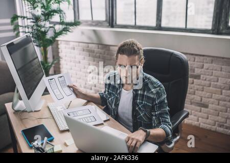Young man in eyeglasses sitting at the desk Stock Photo