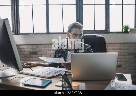 Young man in eyeglasses looking busy and involved Stock Photo