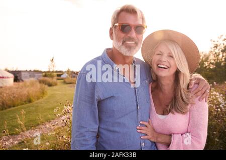 Portrait Of Loving Mature Couple In Countryside Hugging Against Flaring Sun Stock Photo