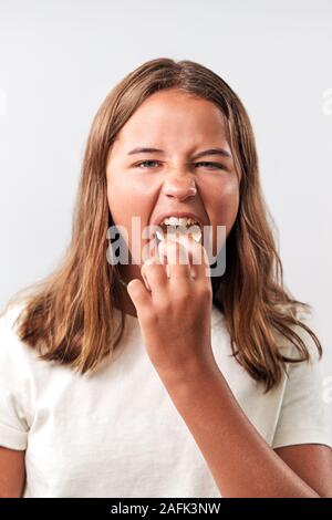 Studio Portrait Of Teenage Girl Eating Unhealthy Snack Of Crisps Against White Background Stock Photo