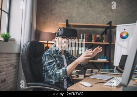Emotional man playing a game using VR headset Stock Photo
