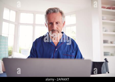 Mature Man In Wheelchair Looking Up Information About Medication Online Using Laptop Stock Photo